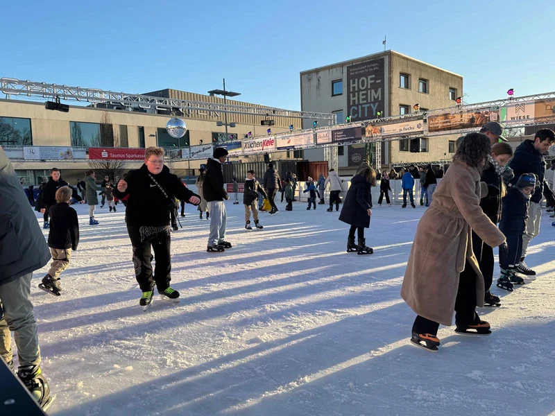 Eislaufende auf der Hofheimer Eisbahn mit Sponsorenbannern am Rand
