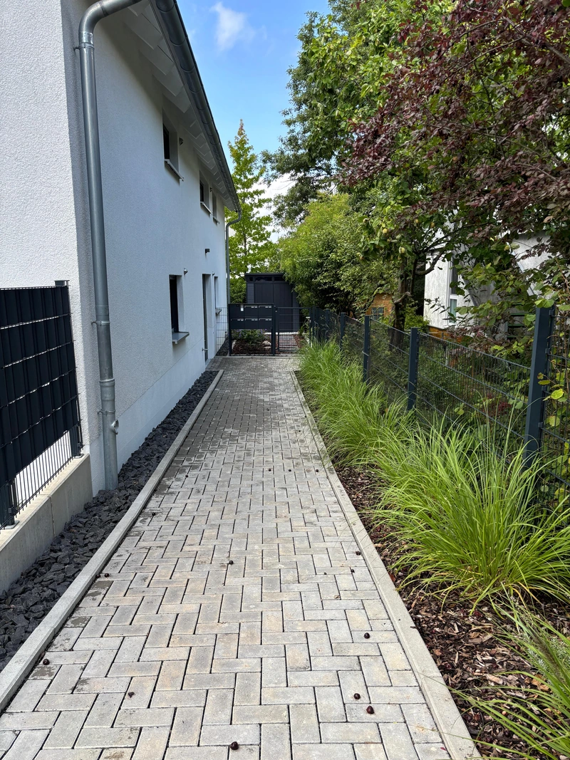 Begrünter Weg entlang des Wohnhauses