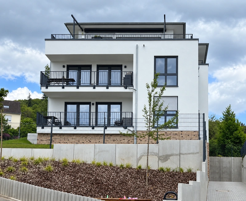 Balkonfassade und Garten am Hang
